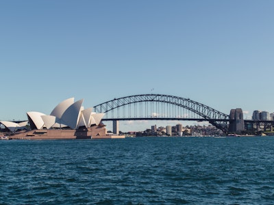 Aussicht vom Wasser aus auf Sydneys Harbour Bridge und das berühmte Opernhaus an einem sonnigen Tag mit blauem Himmel