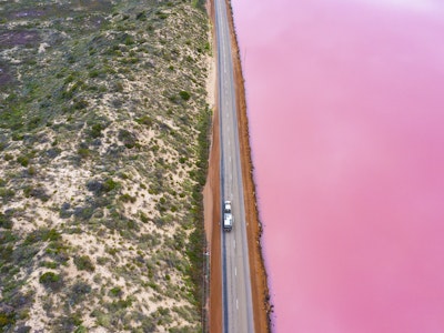 Pinkes Wasser, getrennt von einer Straße vom Land