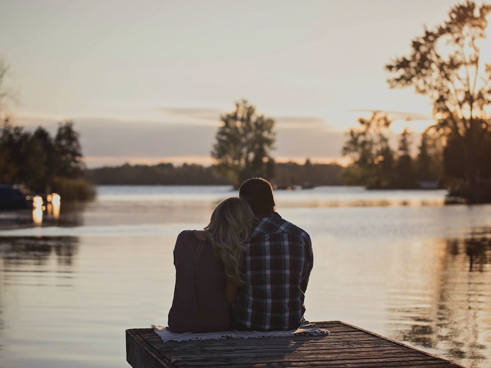 Paar sitzt auf Steg im Sonnenuntergang in Kanada