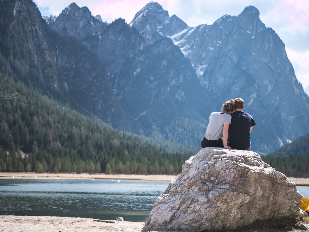 Twee mensen zitten op een rots aan een meer tussen de bergen in Canada