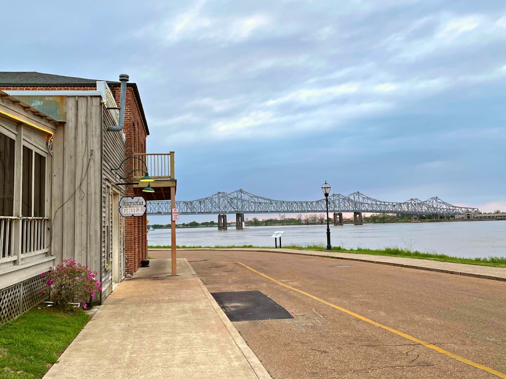 Een restaurant langs de kade met de achtergrond een brug over de Mississippi River