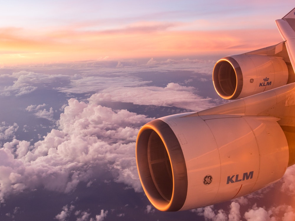 De motoren en vleugel van een vliegtuig die boven de wolken vliegt