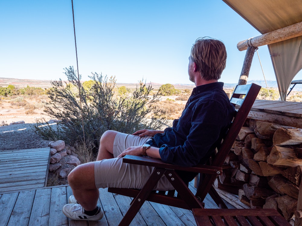 Mann sitzt im luxuriösen Glamping-Zelt mit Ausblick in Moab
