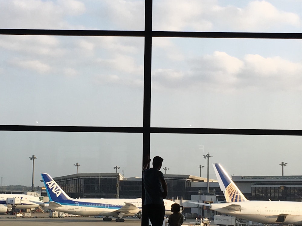 Vader kijkt met zijn kind naar de vliegtuigen op het vliegveld van Los Angeles
