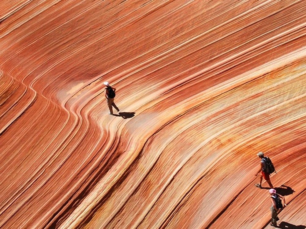 Drei Personen wandern über rote Felslandschaften in Sedona