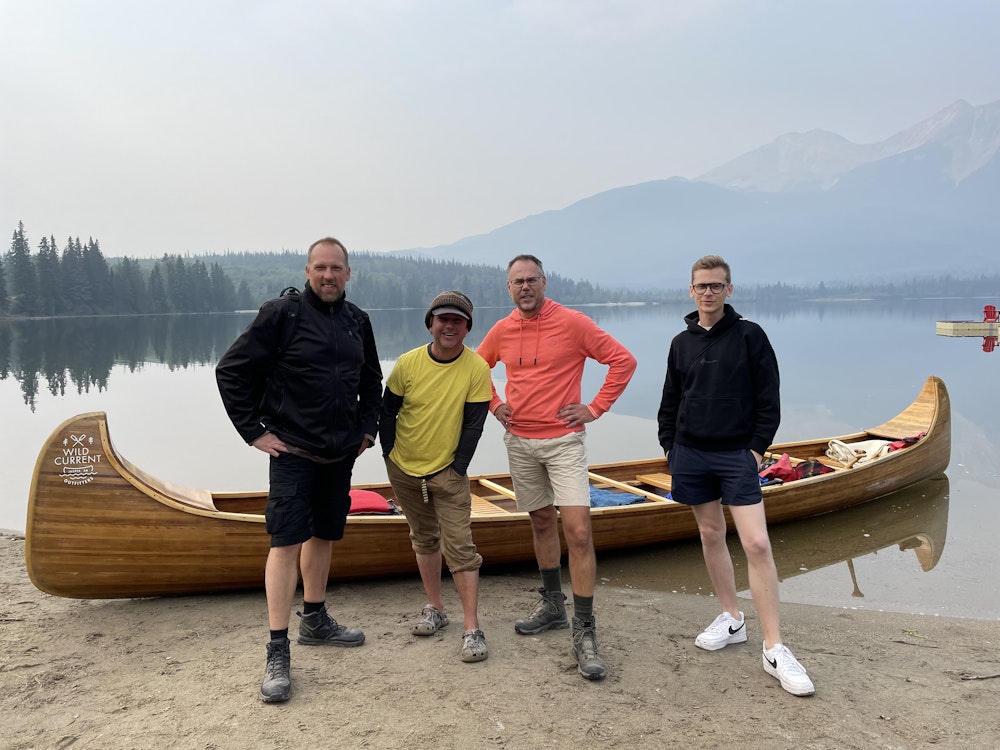 Vrienden poseren voor een Canadese kano, met op de achtergrond een meer