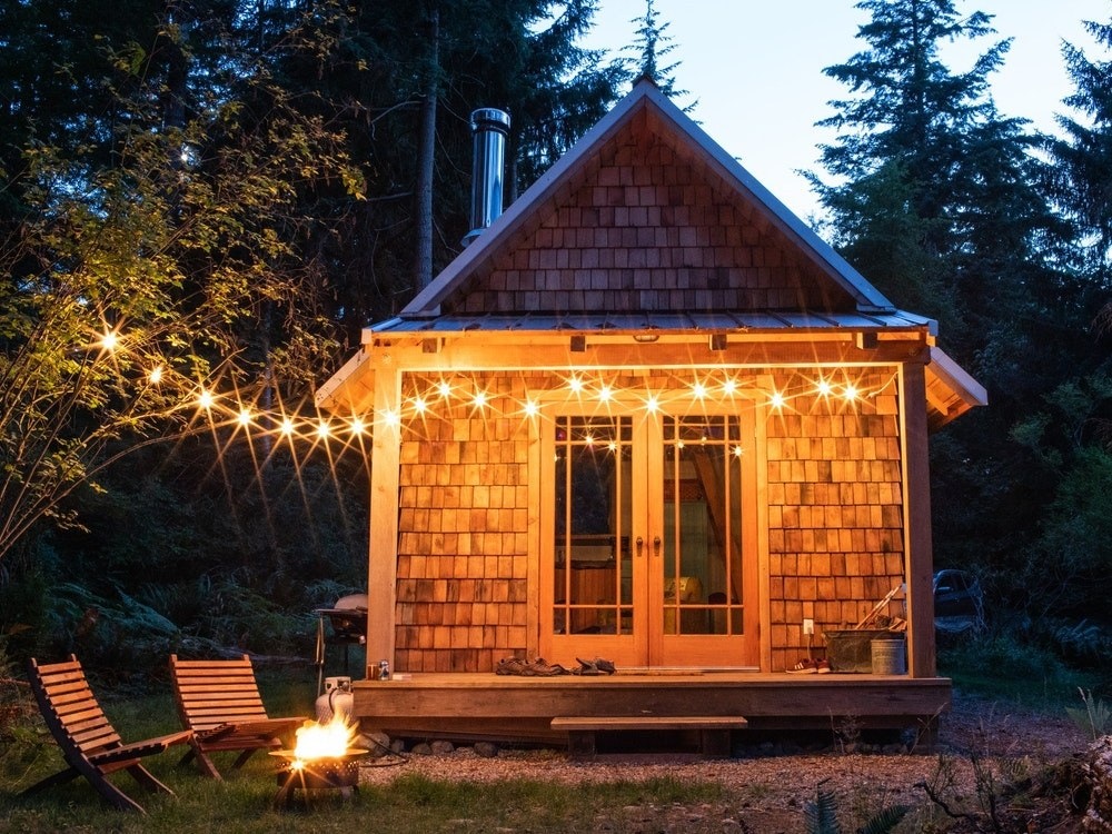 Kleine Holzhütte mit Lichterkette in Abenddämmerung
