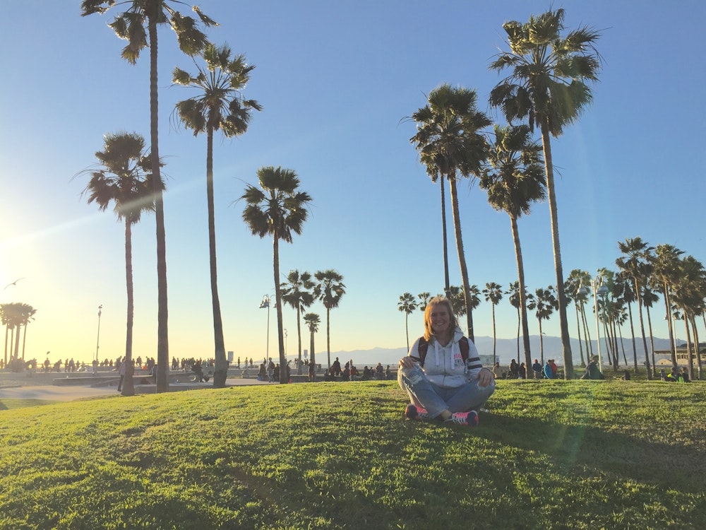 Een vrouw mediteert op het gras bij Venice Beach in de VS