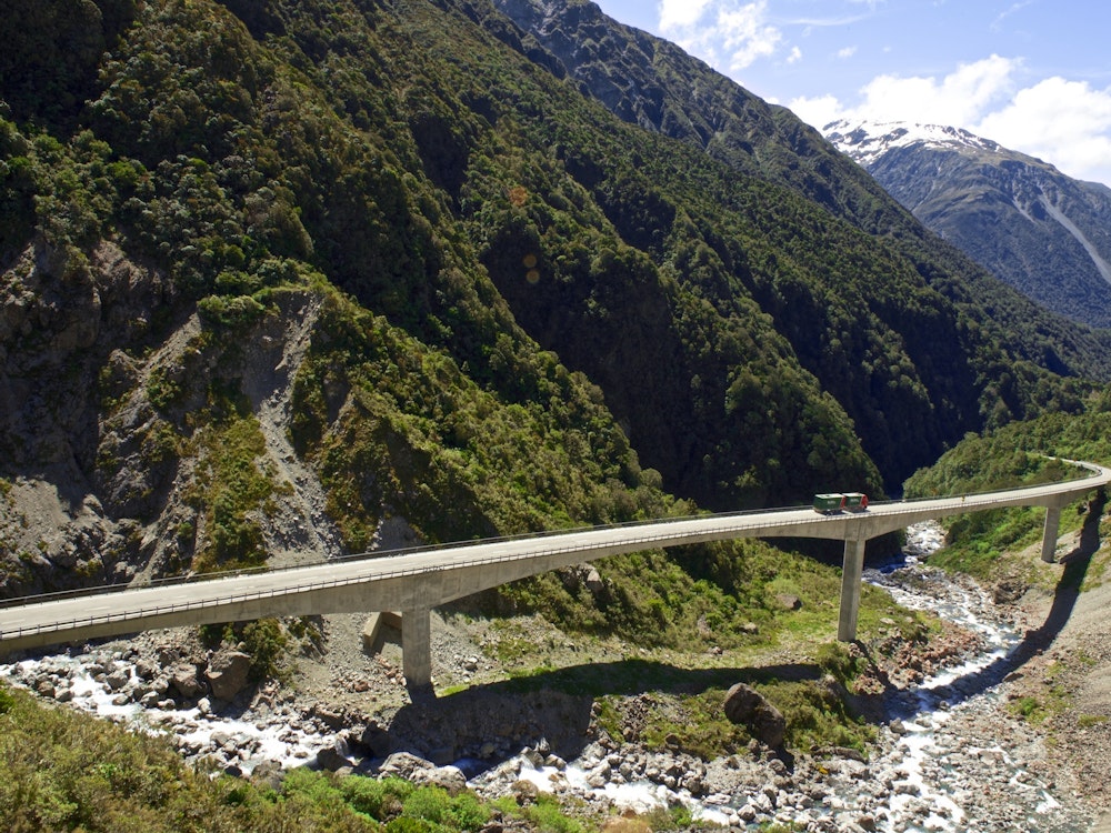 Ein LKW fährt über eine hohe Brücke in den Bergen.