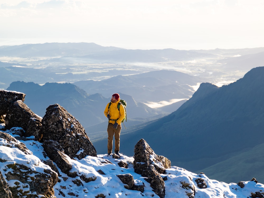 Een man staat op de besneeuwde bergtop van Mount Hikurangi