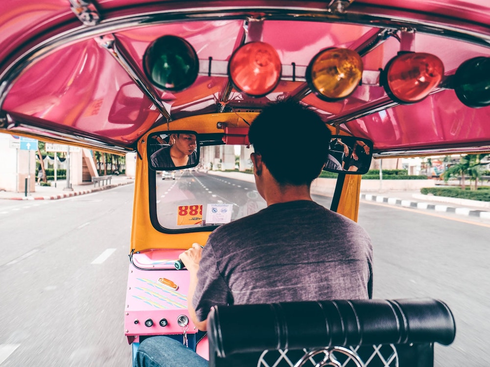 Blick auf Fahrer im pinken Tuk Tuk in Bangkok