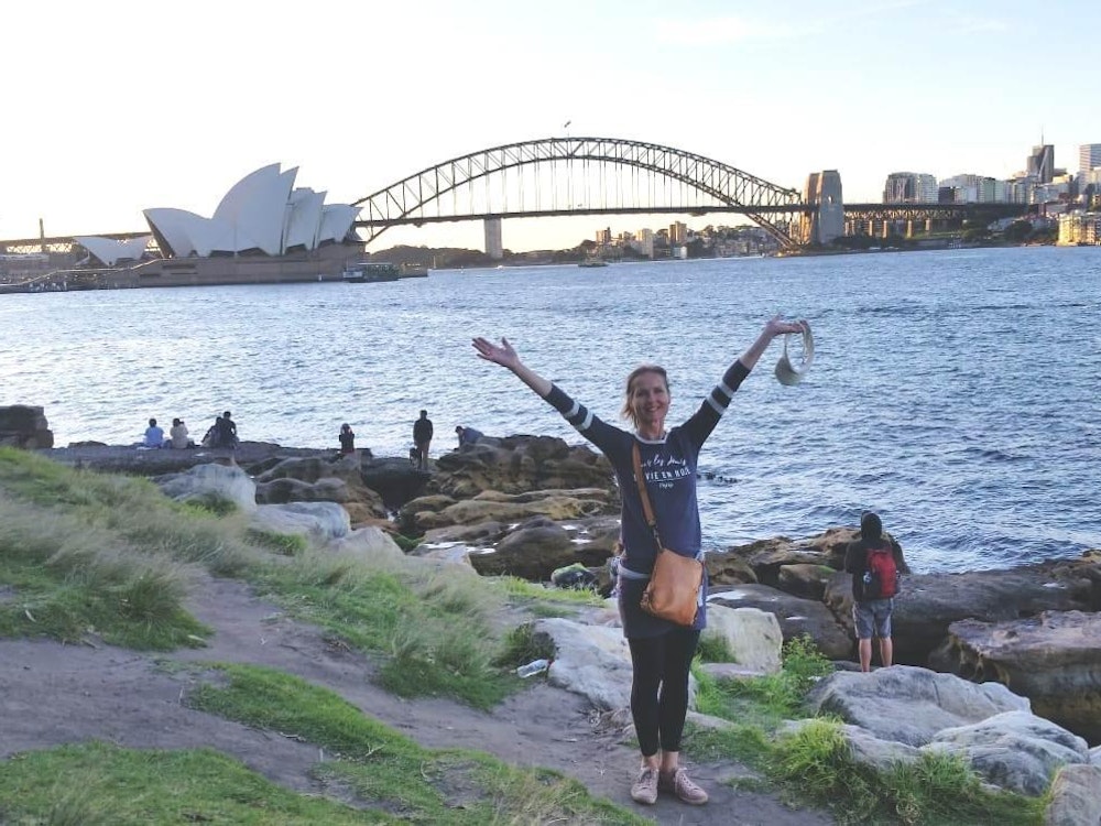 Een vrouw poseert voor de Opera House in Sydney, Australië