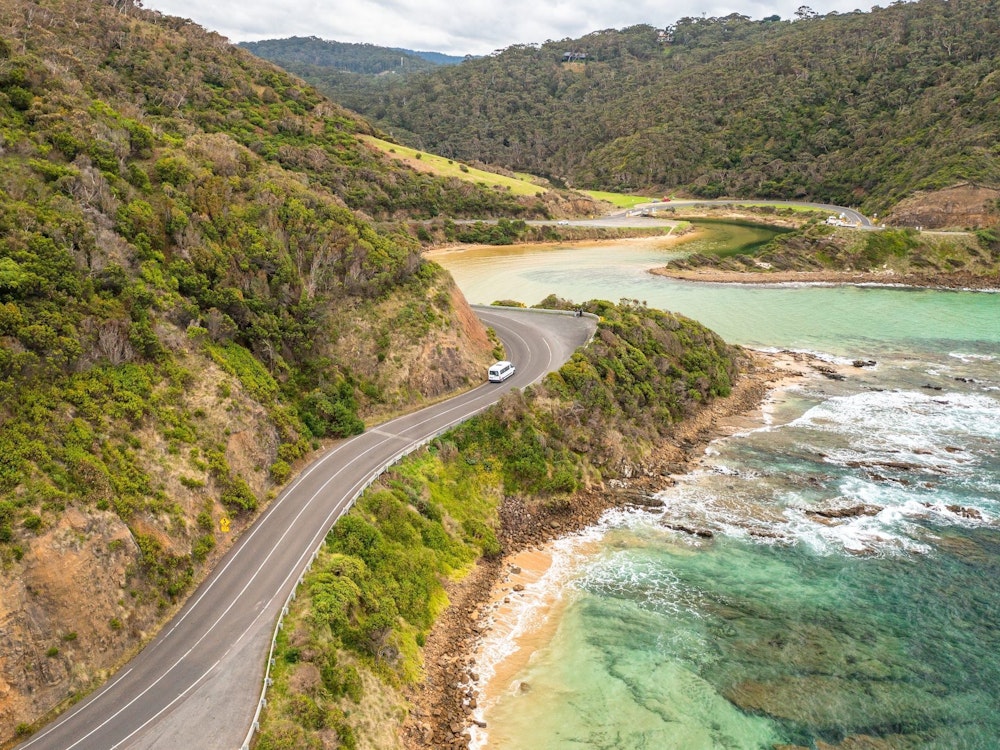 Vogelperspektive auf ein Stück der Great Ocean Road in Australien mit Wald und Ozean