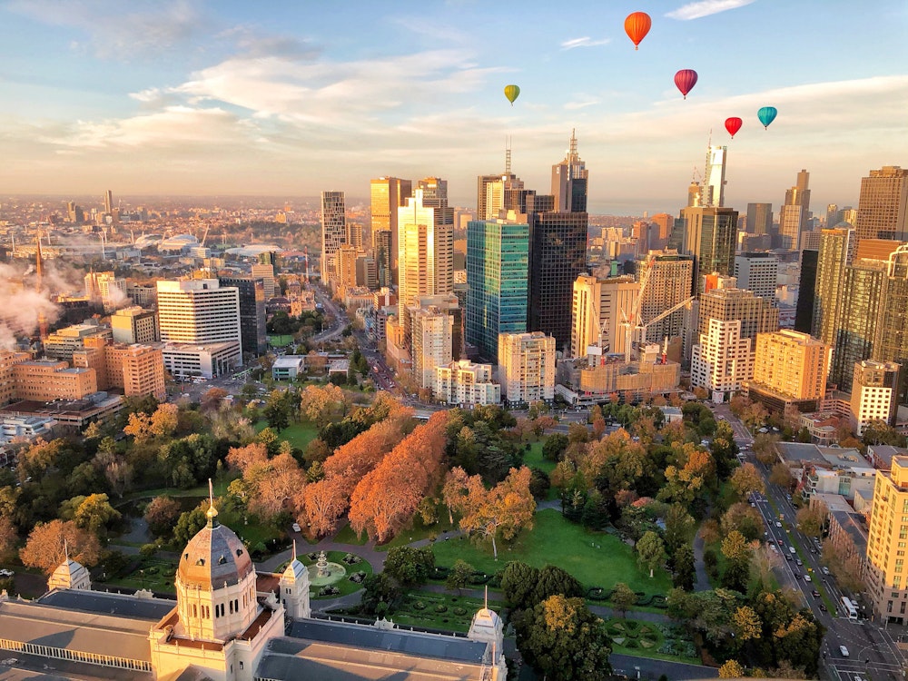 Bunte Heißluftballons fliegen über den Hochhäusern von Melbourne, Australien