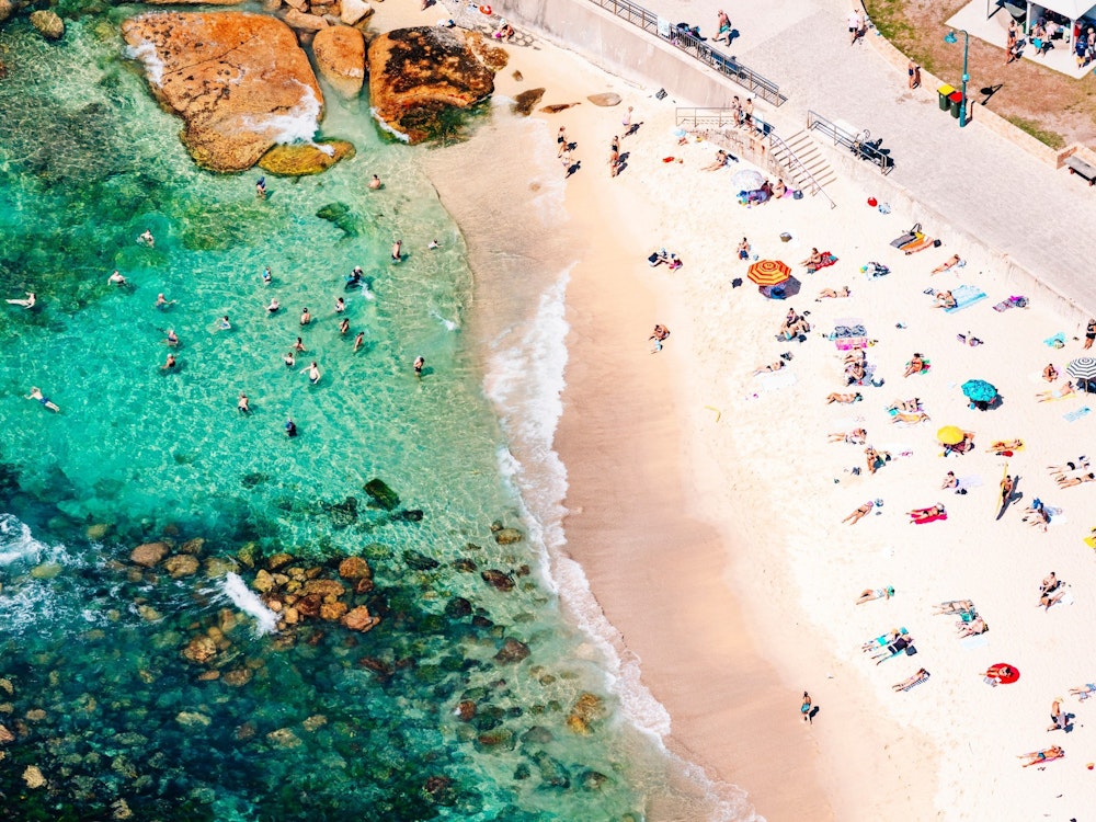 De kust van Bondi Beach waar veel mensen liggen te zonnebaden op het hagelwitte strand