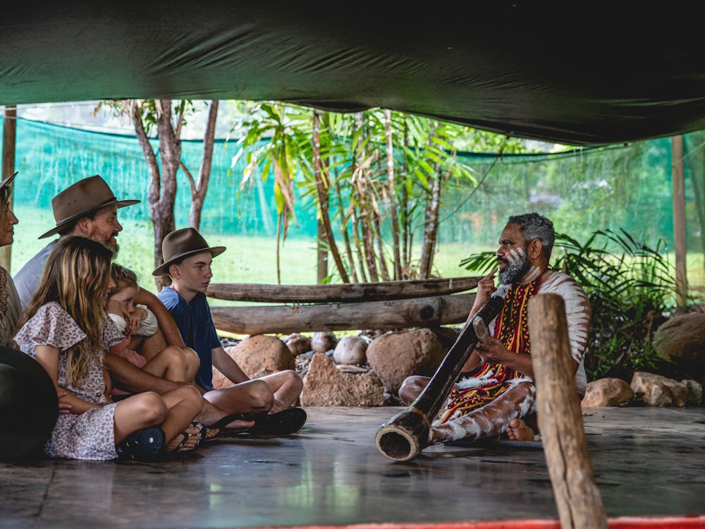 Man heeft didgeridoo in zijn hand en vertelt de toeristen over zijn Aboriginal cultuur