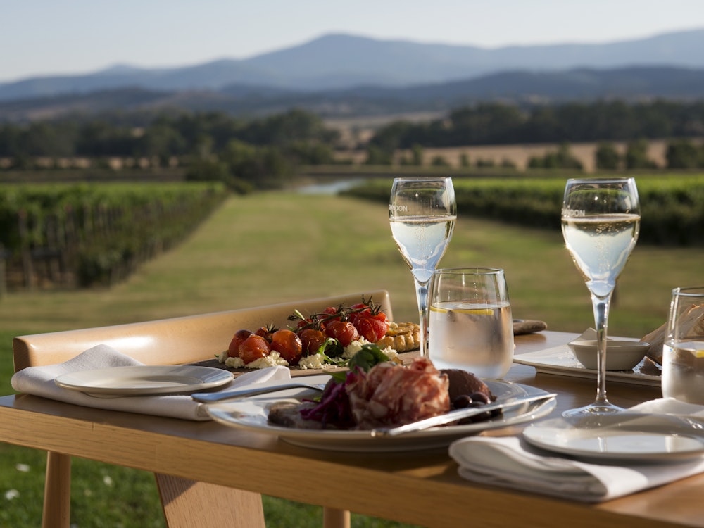 Een tafel vol met eten en drinken met uitzicht over de wijngaarden