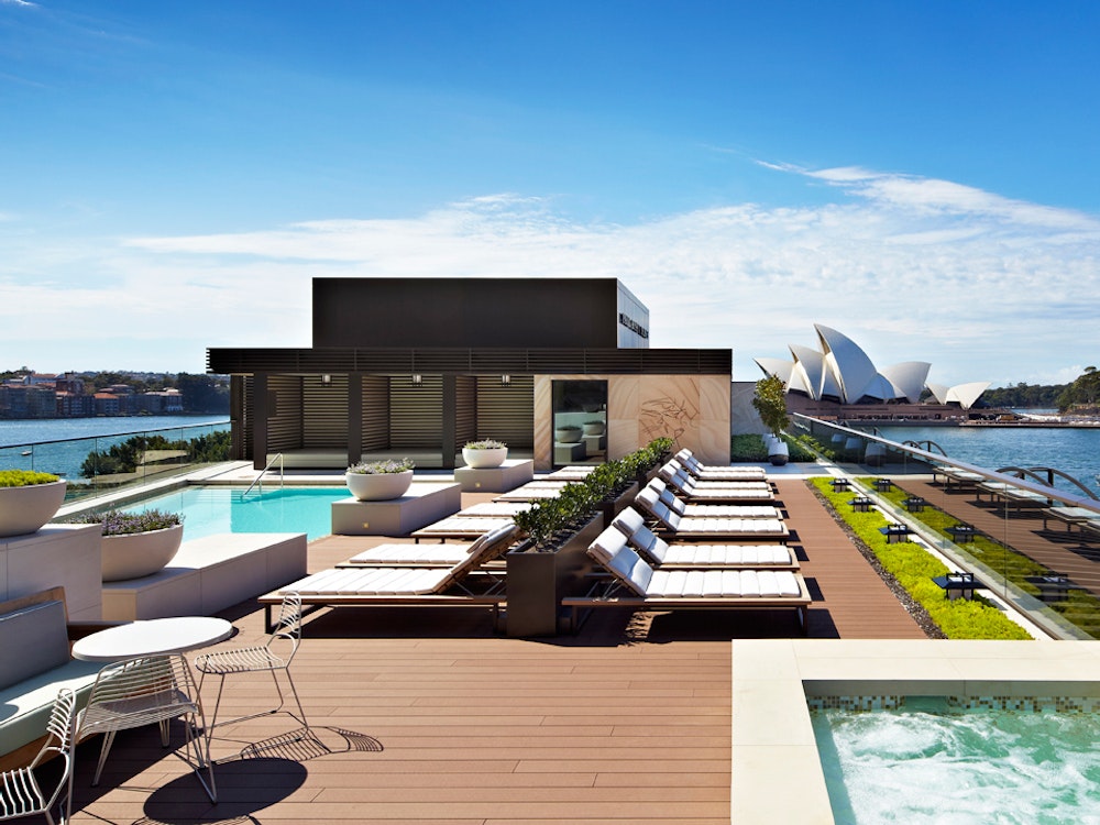 Luxe zwembad en ligstoelen met uitzicht over de Opera House in Sydney
