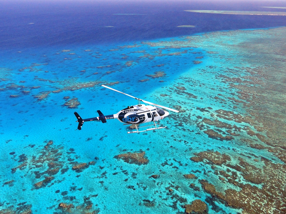 Een helikopter vliegt over de heldere koraalzee van het Great Barrier Reef