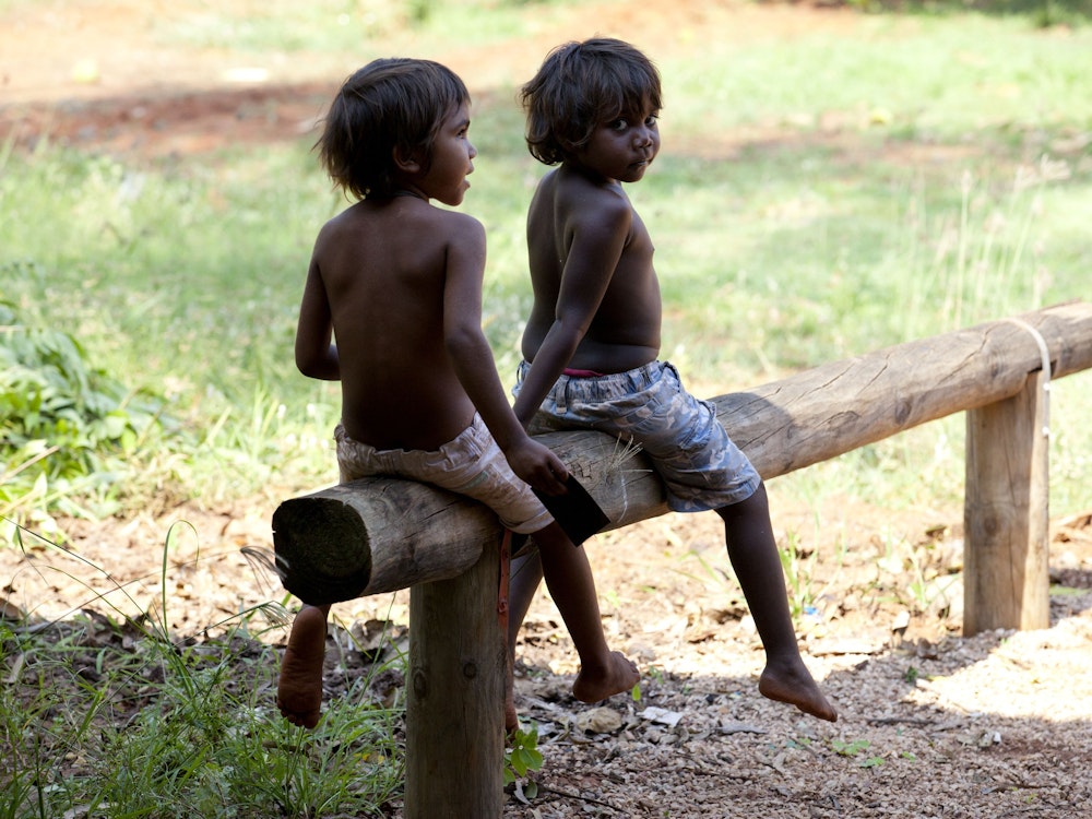 Aboriginal Kinder sitzen auf einem Holzbalken