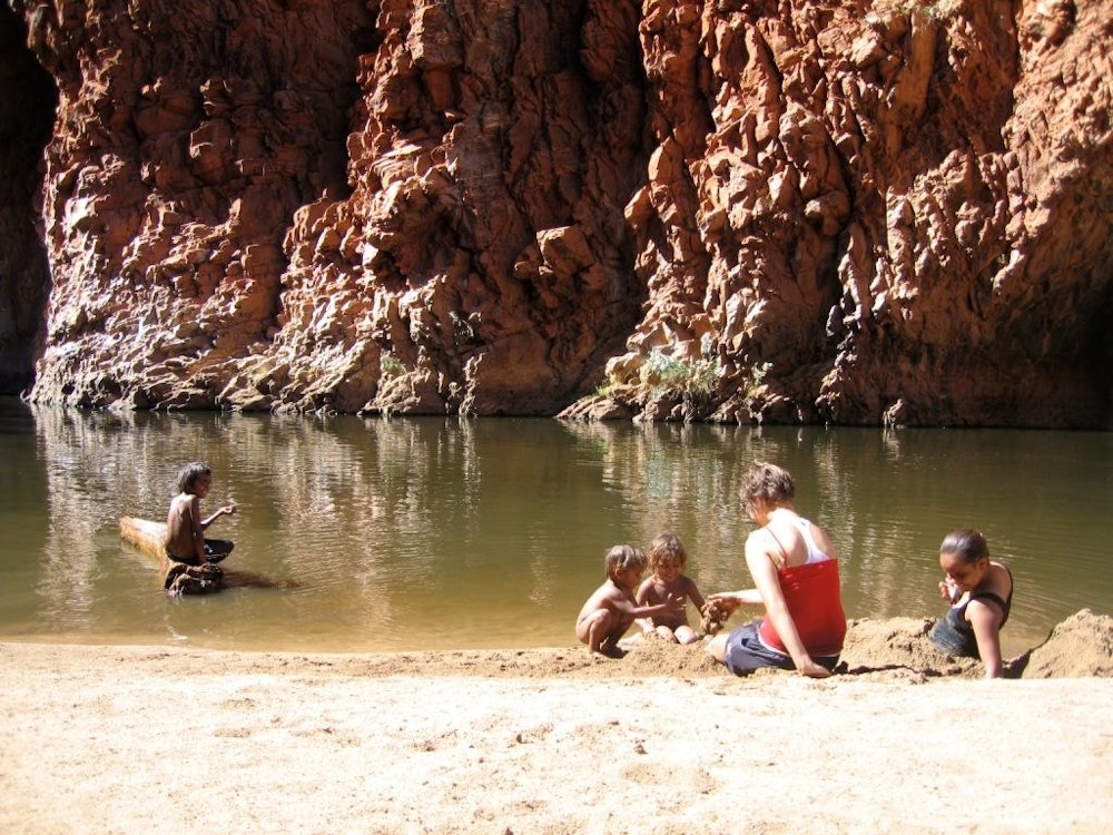Personen schwimmen mit Aborigines in Wasserloch