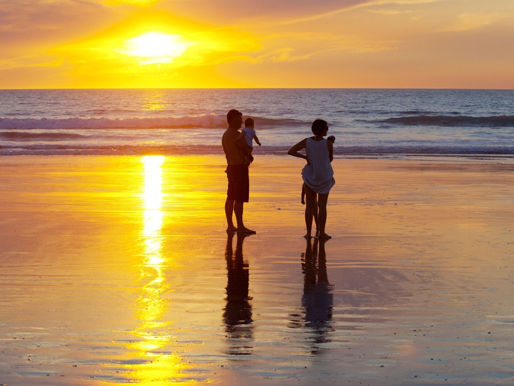 Gezin op het strand tijdens zonsondergang in Australië