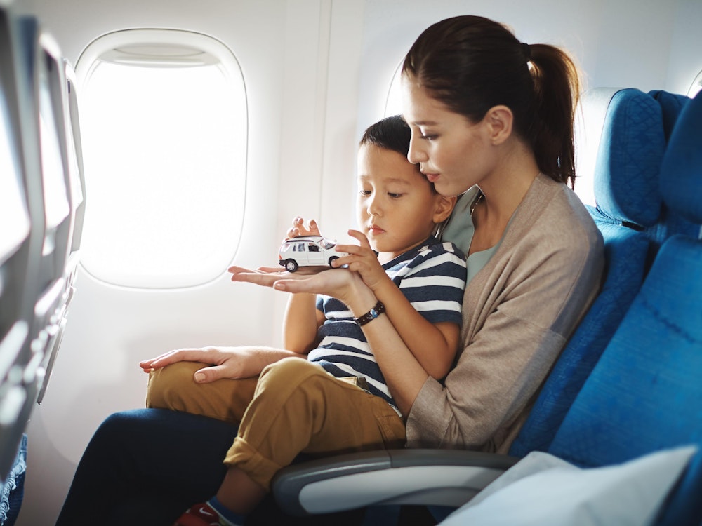 Moeder zit met haar zoontje op schoot in een vliegtuig