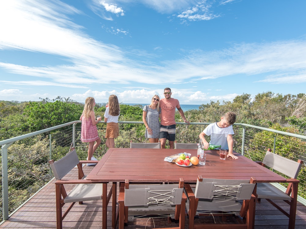 Familie op een balkon met eettafel en uitzicht over de bossen