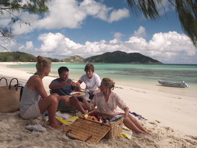 Familie mit Teenagern macht Picknick am Strand von Lizard Island