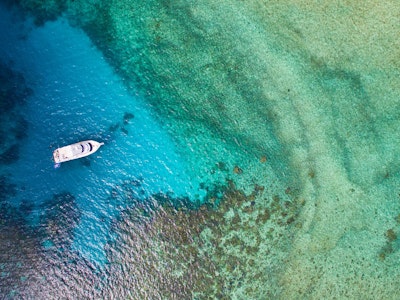 Ausschnitt eines australischen Korallenriffs aus der Vogelperspektive mit weißem Boot