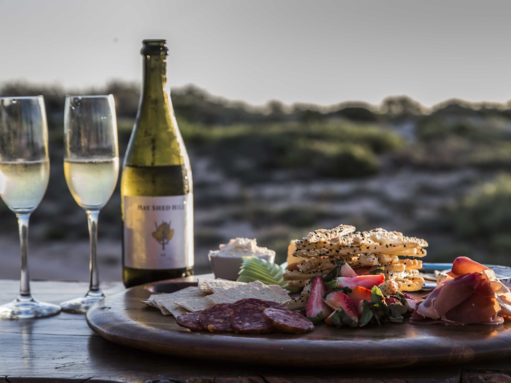 Een borrelplank en twee glazen champagne met uitzicht over de heuvels in Australië
