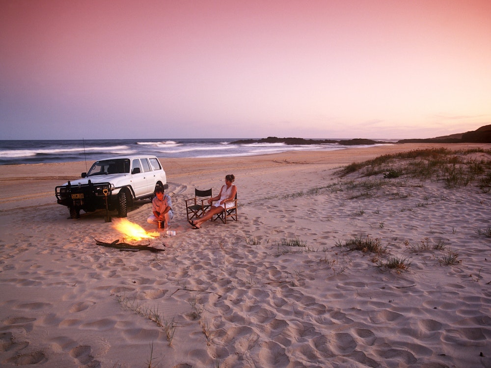 Een koppel geniet van de zonsondergang op een verlaten strand in Australië