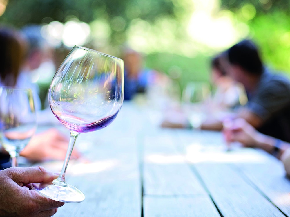 Blick auf leeres Winglas und Tisch mit Leuten bei Weinverkostung in Tasmanien