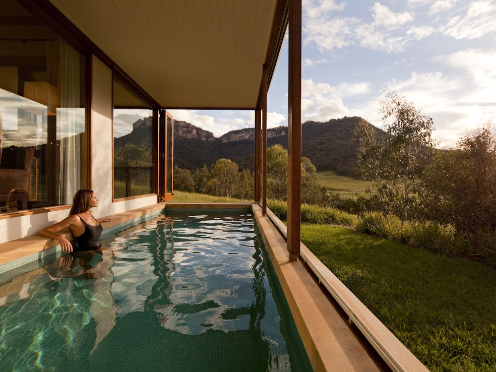Vrouw staat in zwembad en bekijkt het uitzicht over de Australische bush