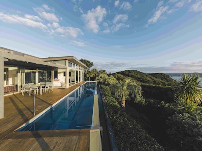 Een luxe 'infinity pool' omringd door bomen en planten in Nieuw-Zeeland
