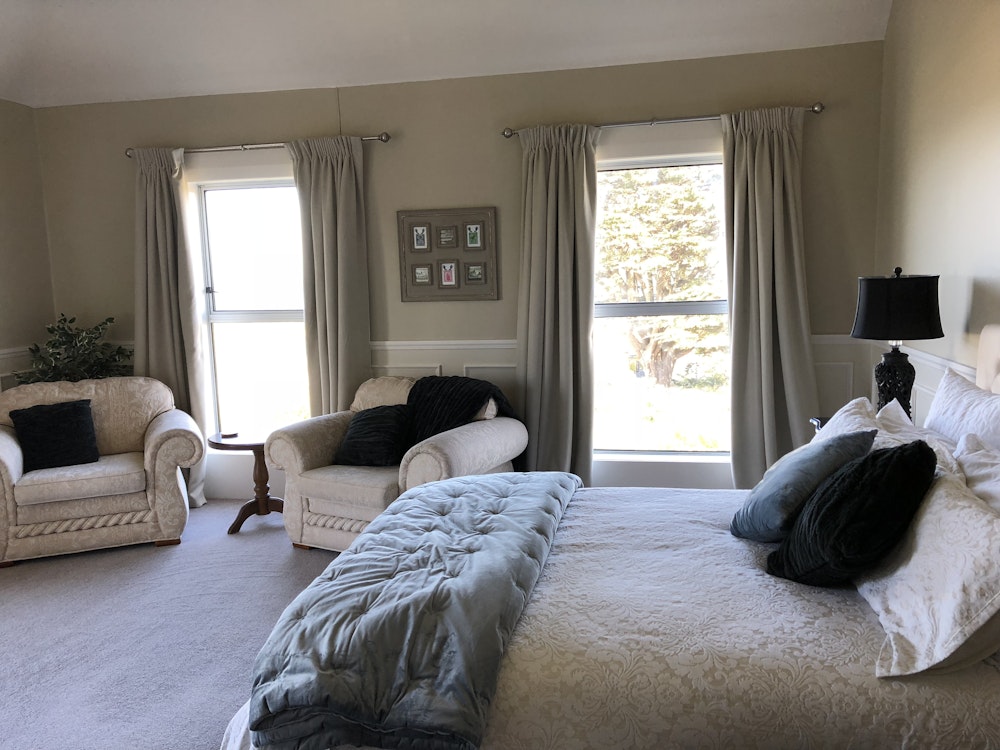 Een slaapkamer met tweepersoonsbed en twee fauteuils in Dunedin
