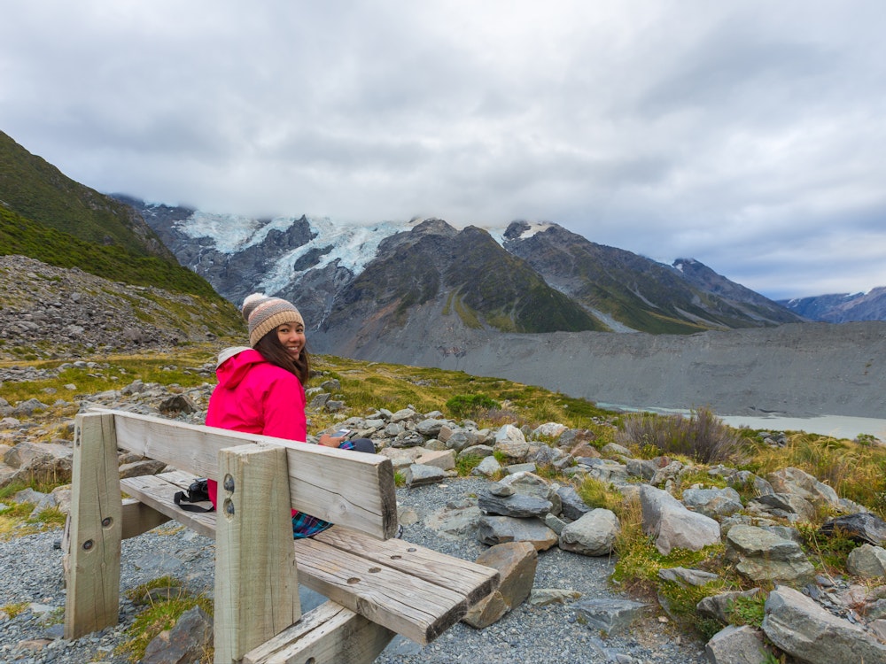 Een vrouw zit op een bankje en kijkt achterom in Mount Cook NP Nieuw-Zeeland