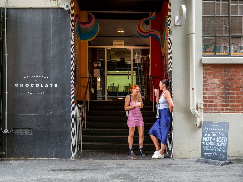 Twee vrouwen drinken koffie in de deuropening van de Wellington Chocolate Factory