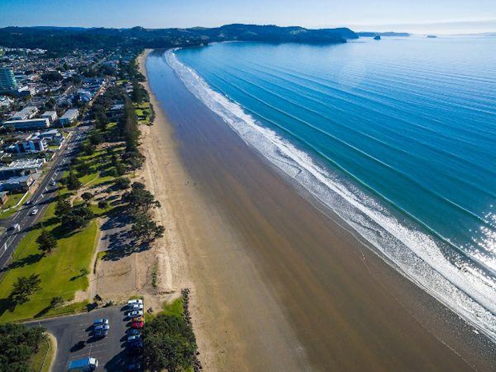 Aerial view of a long stretch of coast with golden sand and blue water