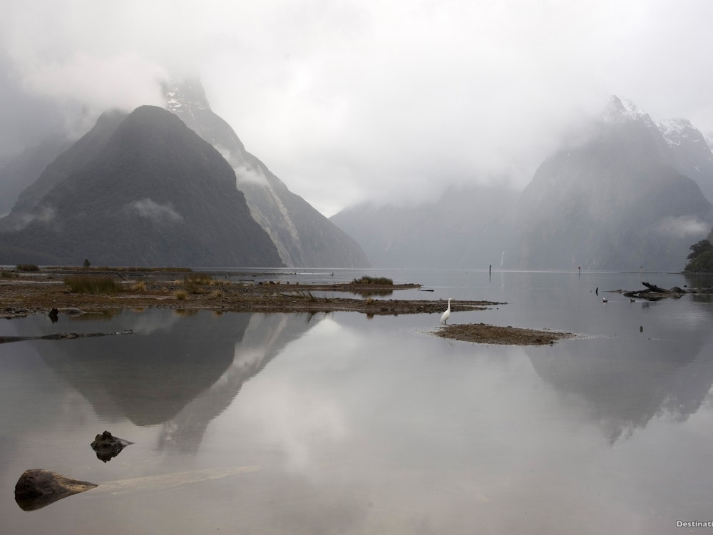 Low hanging clouds over cliffs with a mirror reflection in the lake
