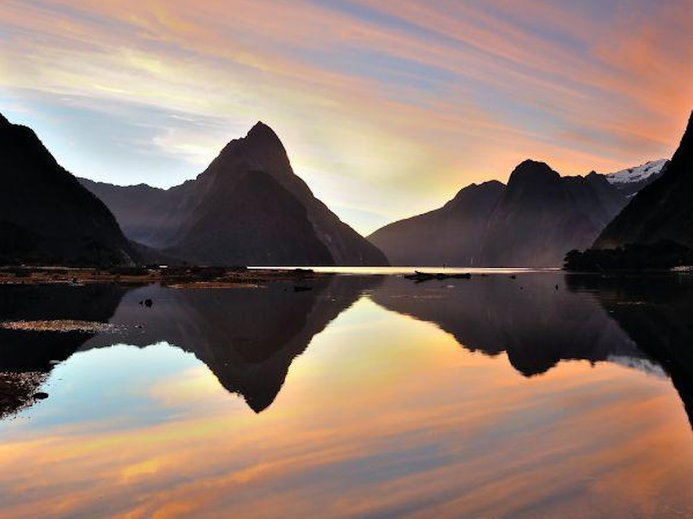 Mountains peaks reflecting in clear water at sunset