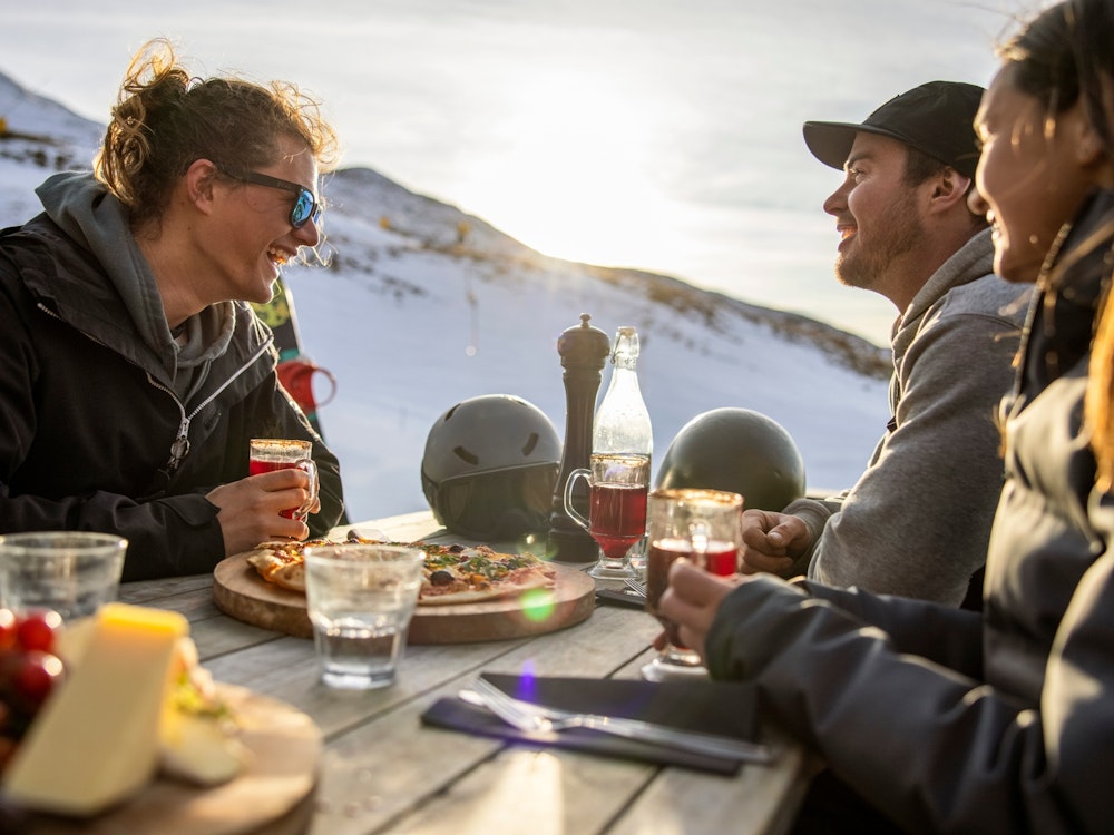 Two men and a woman sitting at a table on ski slope