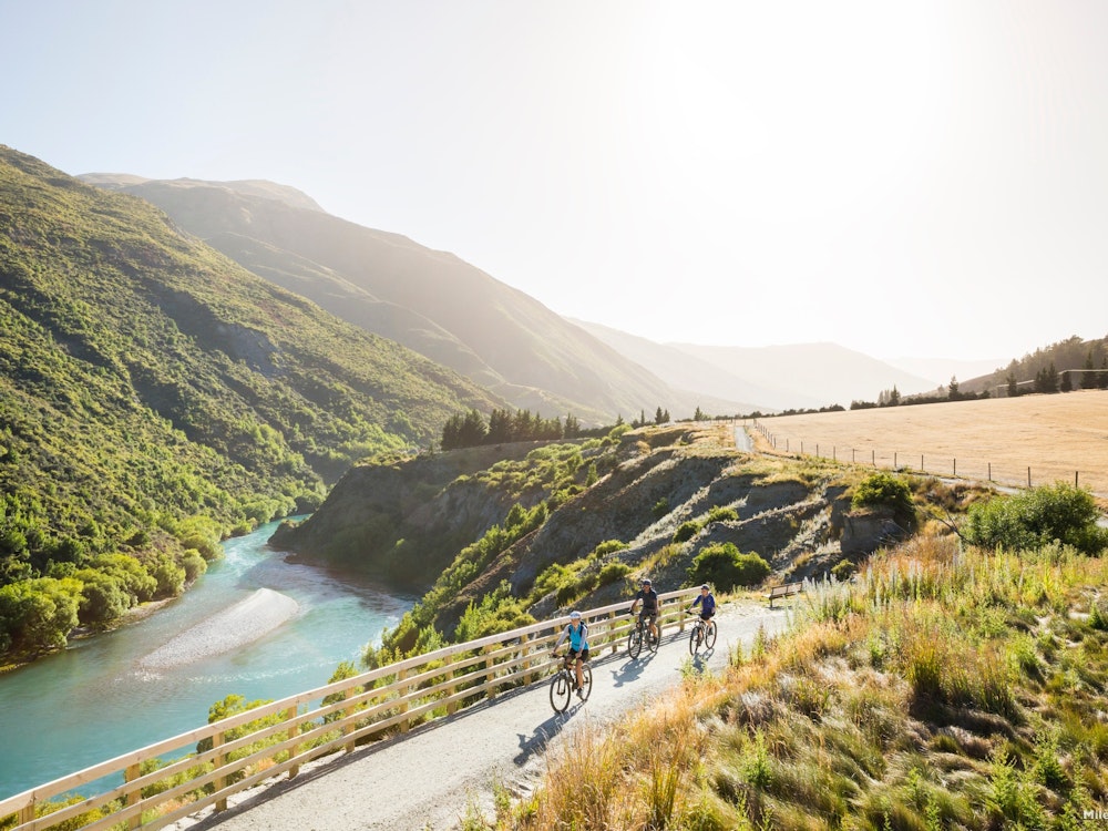 A group of cyclists riding on a road through a mountainous valley