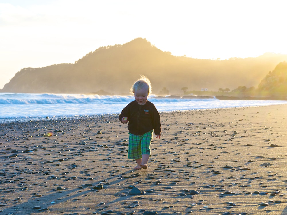 Een klein kind loopt over het strand bij Coromandel in Nieuw-Zeeland
