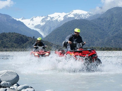 Twee mensen rijden in een quad door een ondiep meer in Nieuw-Zeeland