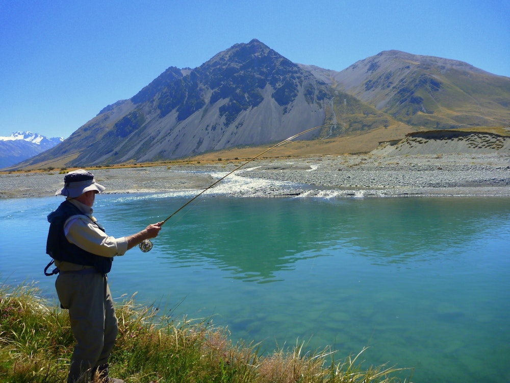 Man doet aan vliegvissen in een rivier in Wanaka Nieuw-Zeeland