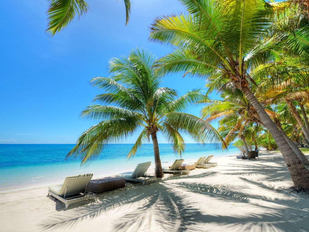 Een hagelwit strand met ligbedjes en palmbomen op Fiji