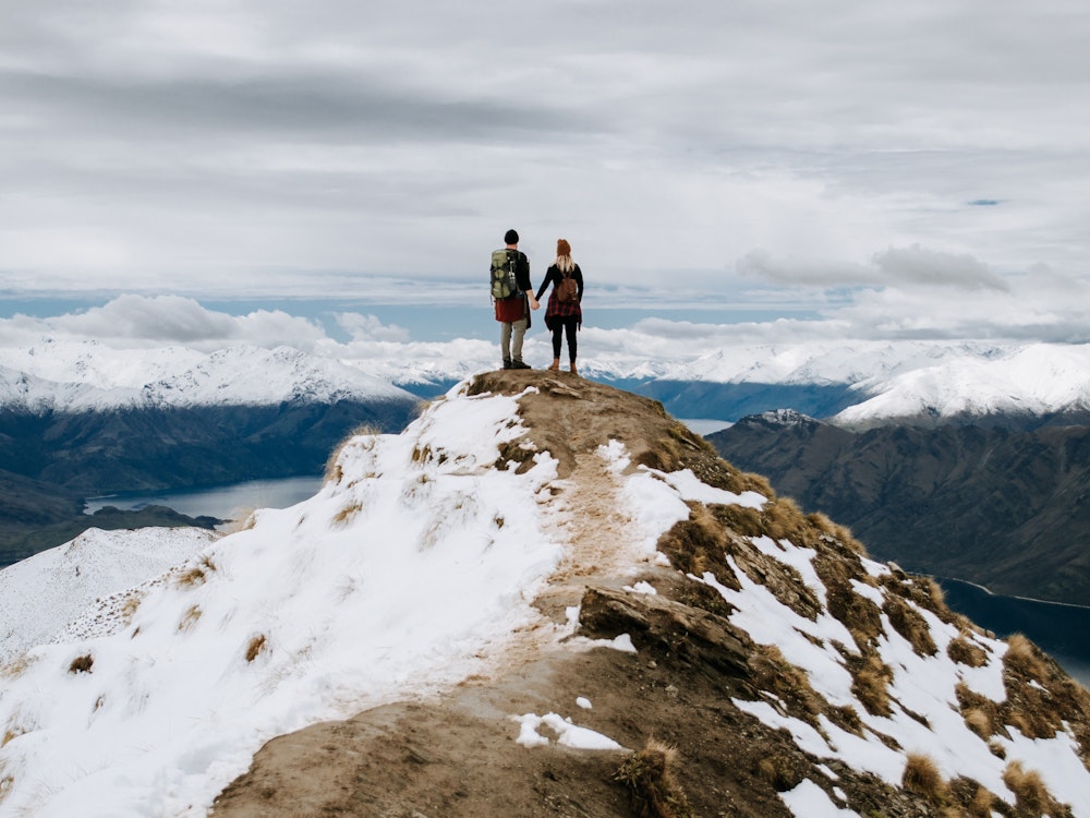 Een koppel staat op de top van een besneeuwde berg in Nieuw-Zeeland