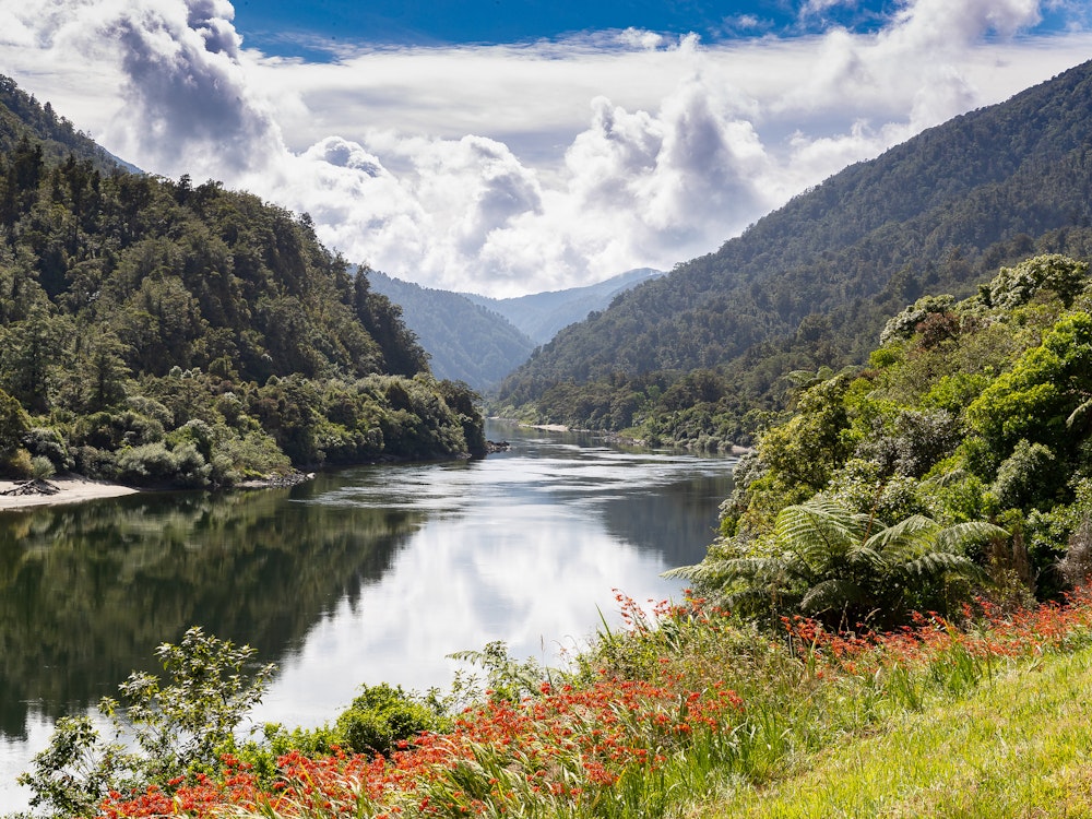 De oever van een rivier in Nieuw-Zeeland met uitzicht over het bergachtige landschap
