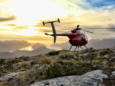 Helikopter die landt op een berg met uitzicht op een meer.